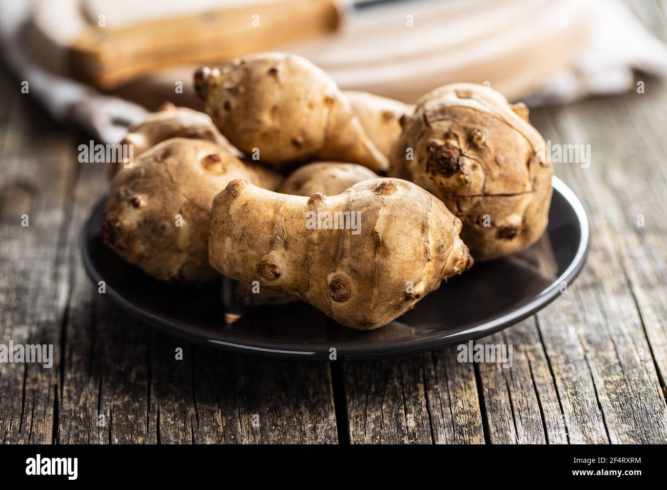 Raw jerusalem artichoke. Topinambur vegetable root on plate Stock Photo