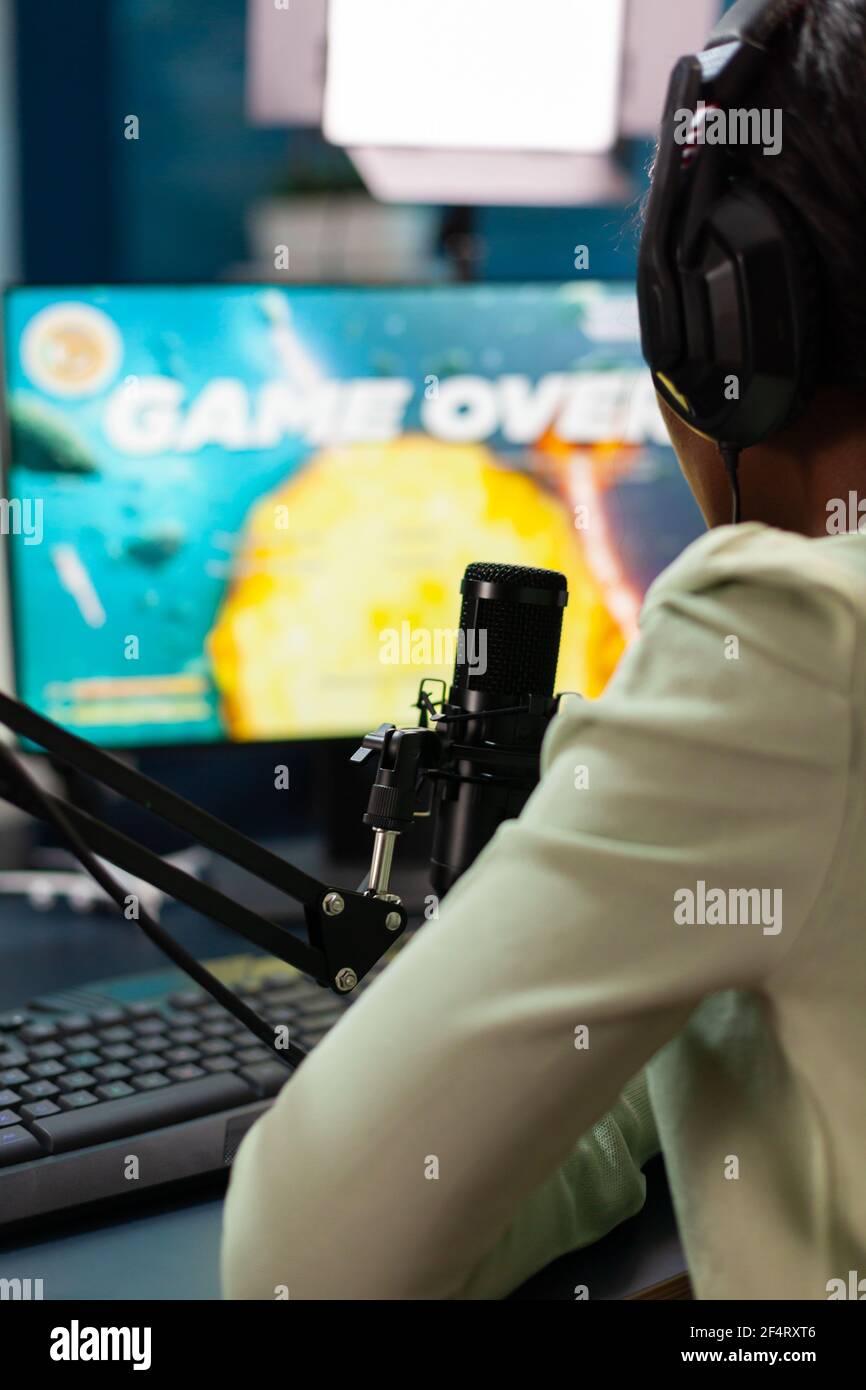 Afro streamer losing online championship being disappointed game over. Professional gamer streaming online video games with new graphics on powerful computer. Stock Photo