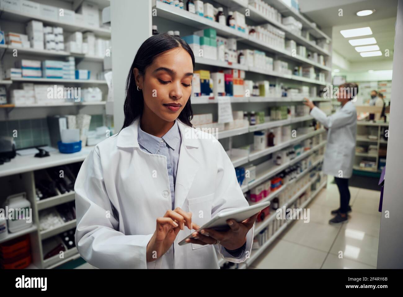 Young female woman wearing labcoat working in chemist using digital tablet Stock Photo