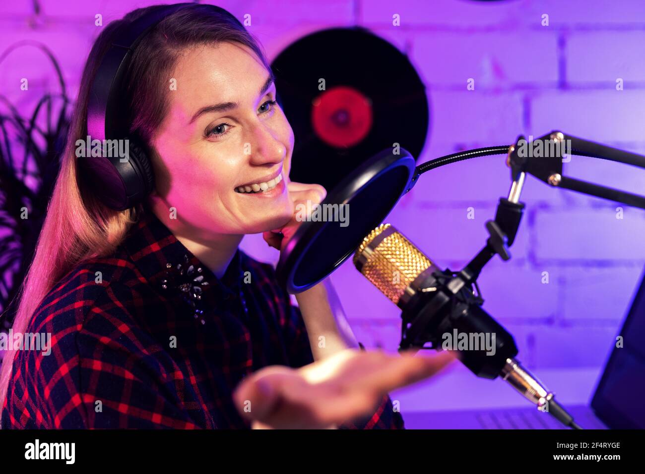 online podcasting - woman podcaster or radio host enjoying work in studio. speaking in microphone Stock Photo