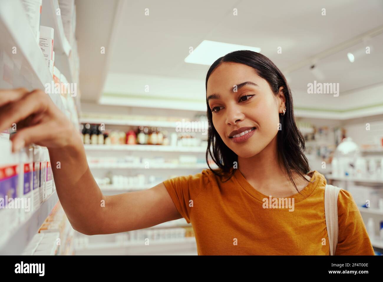 Young smiling woman in casual clothing buying medicine in a pharmacy Stock Photo
