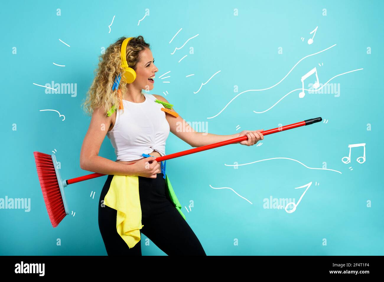Funny housewife use broom like a rock guitar. cyan background Stock Photo
