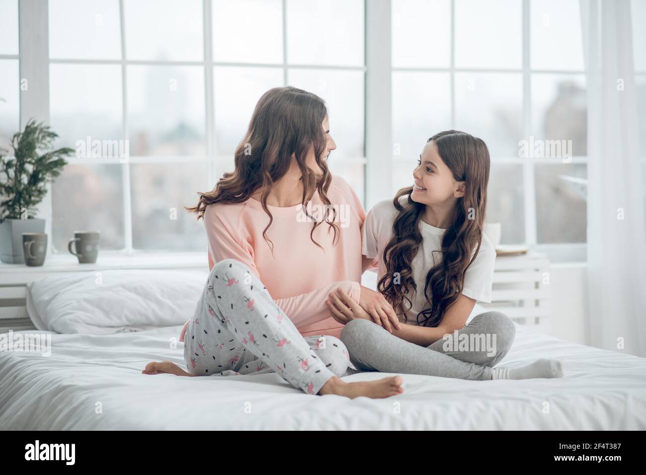 Mom and daughter in pajamas sitting on bed Stock Photo