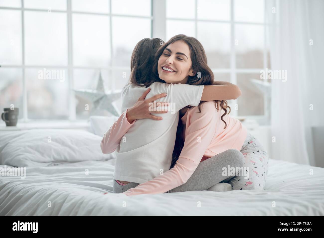 Daughter with back to camera and mom hugging Stock Photo