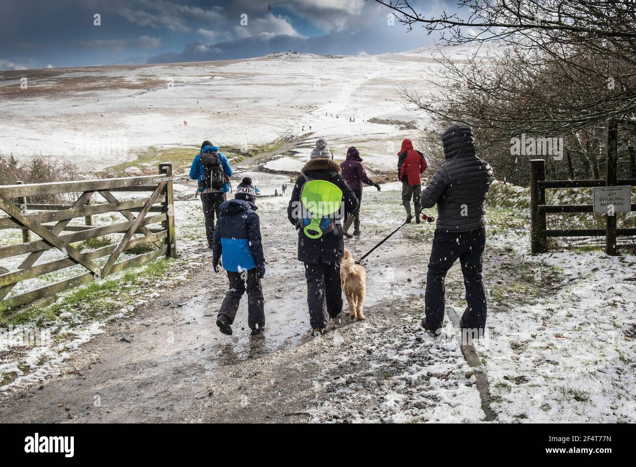 A family enjoying walking in the snow on the wild rugged Rough Tor on Bodmin Moor in Cornwall. Stock Photo