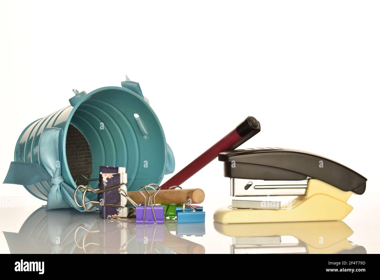 One stationery stapler, several blinders, two pens and a decorative metal bucket on a white background. Stock Photo