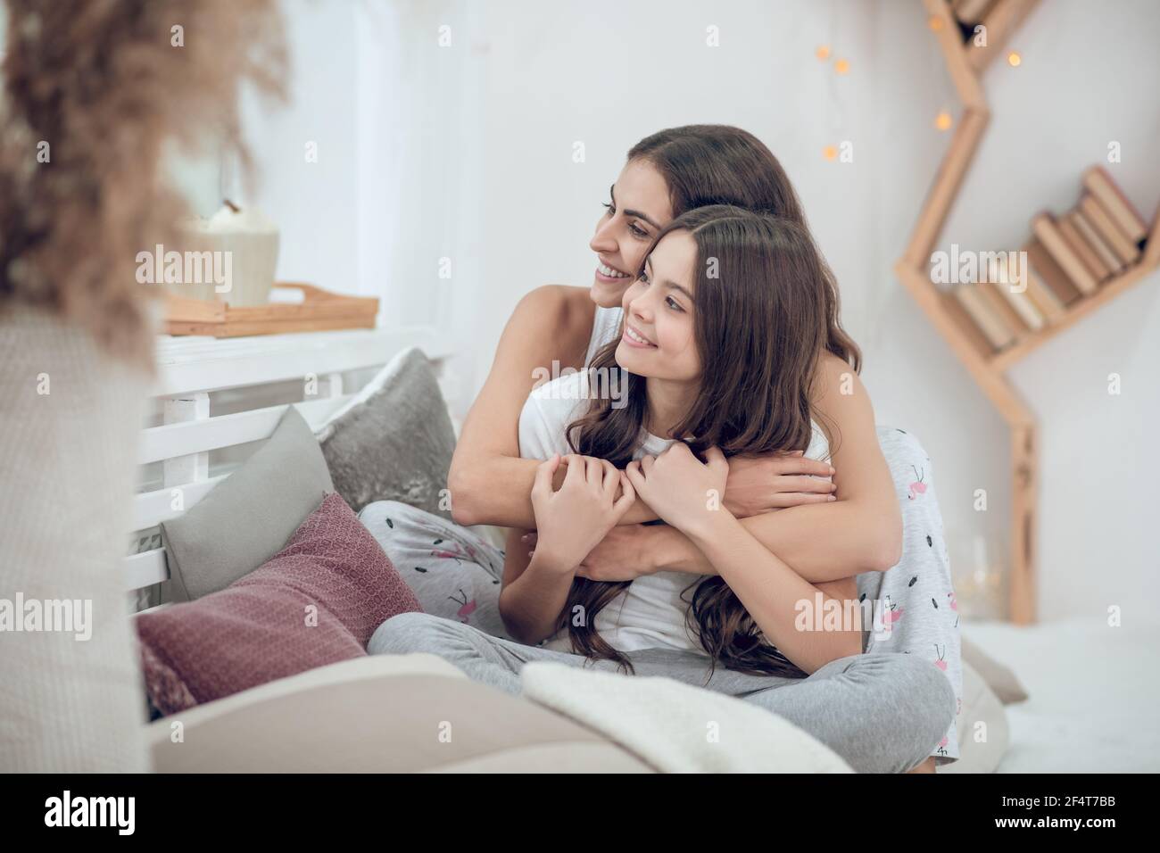 Happy mom and daughter sitting hugging at home Stock Photo