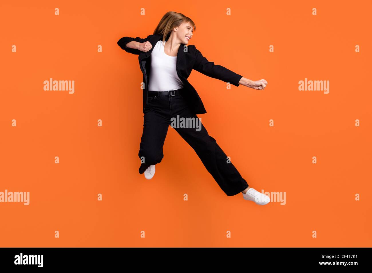 Profile side photo of young beautiful funky smiling woman doing karate fight kick isolated on orange color background Stock Photo
