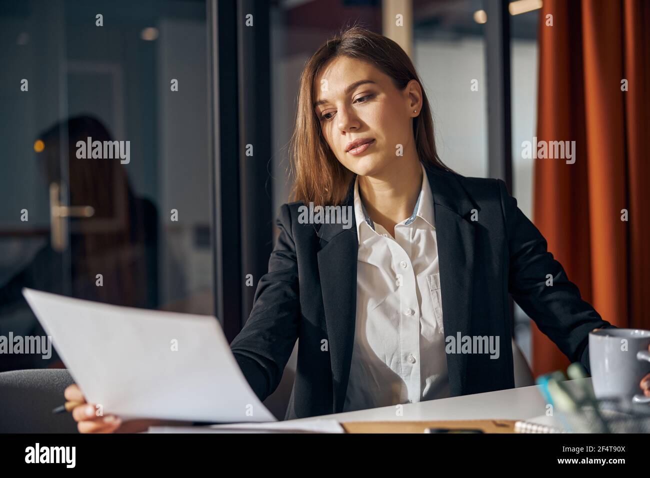 Focused young draftswoman scrutinizing a technical drawing Stock Photo