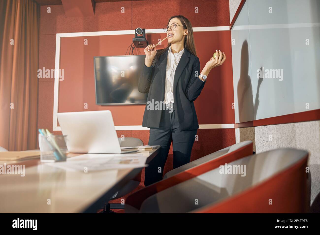 Female employee in eyeglasses and a pantsuit pondering over something Stock Photo