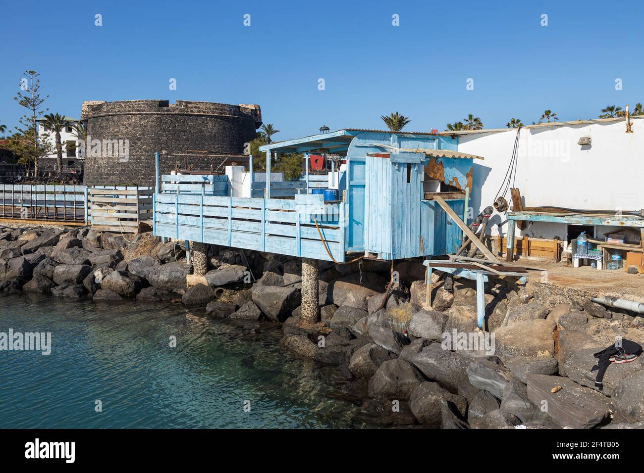 Blue wooden fish cleaning station on the coast next to the El Castillo, an 18th-century defensive tower in Caleta de Fuste, Fuerteventura, Canary Isla Stock Photo