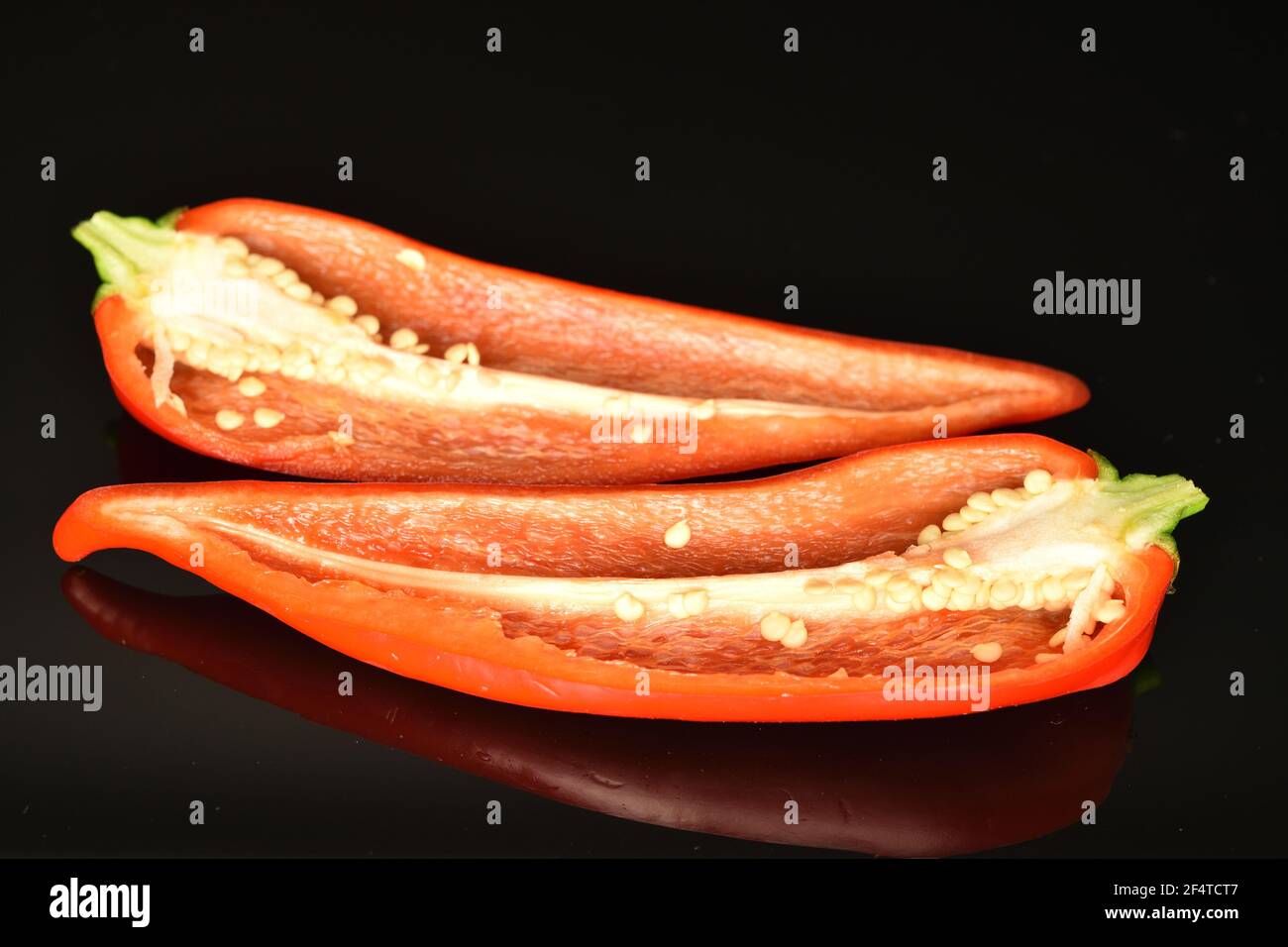 Two halves of fresh ripe tasty sweet red Kapia pepper on a black