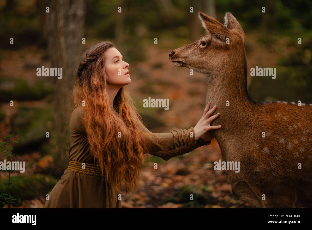 Redhead girl with deer in a long dress Stock Photo