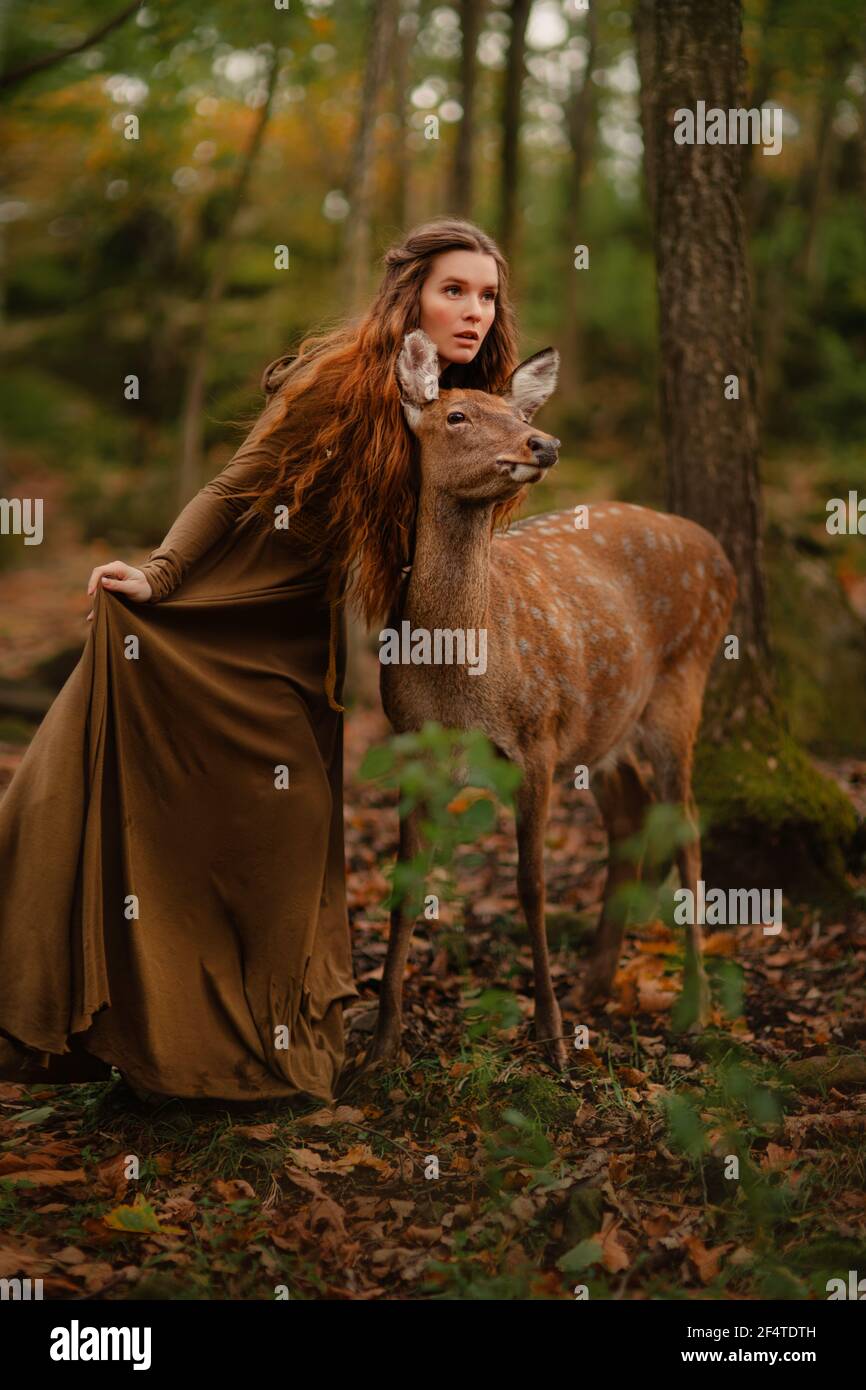 Redhead girl with deer in a long dress Stock Photo
