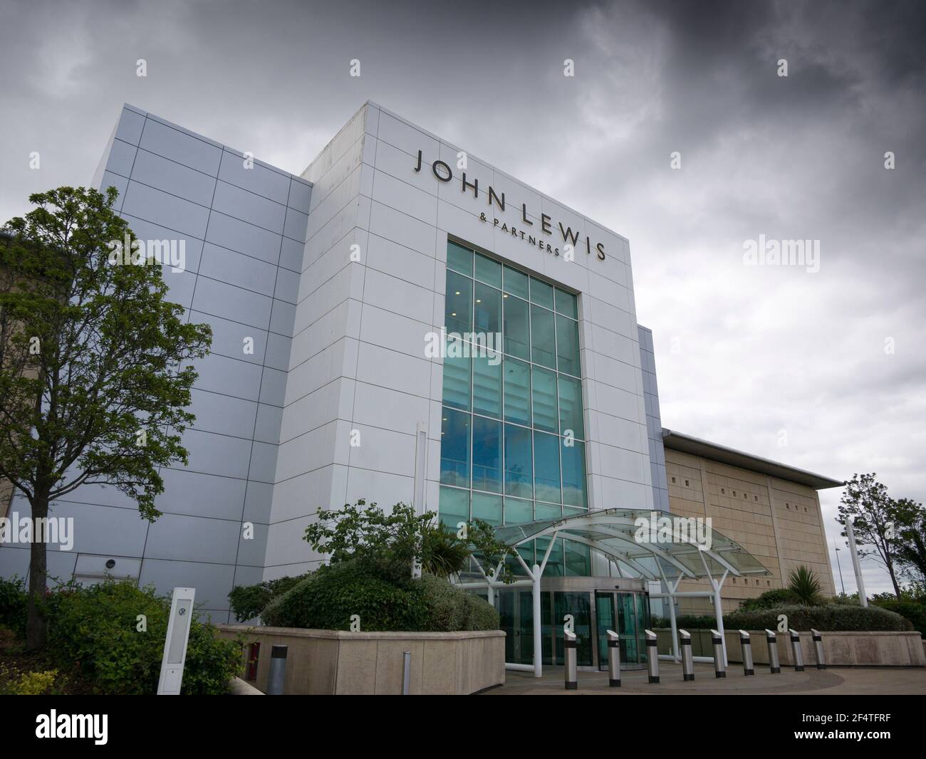 The entrance to John Lewis & Partners store under dark clouds at The Mall Shopping Centre, Cribbs Causeway, Gloucestershire near Bristol, England. Stock Photo
