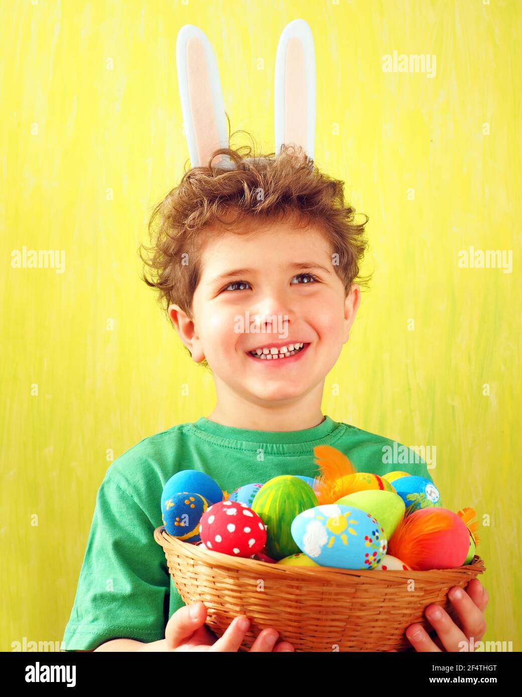 Cute little boy with bunny ears on his head holding a wicker basket