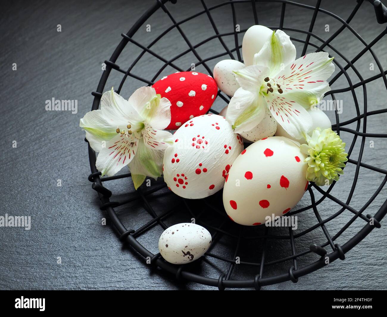 Easter eggs in a metal basket close up over a black stone background Stock Photo