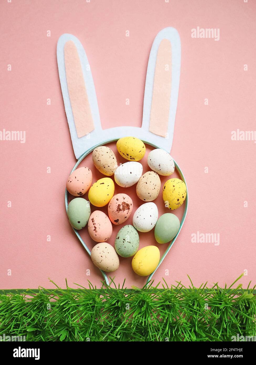 Easter bunny ears with colored eggs on pink background Stock Photo - Alamy
