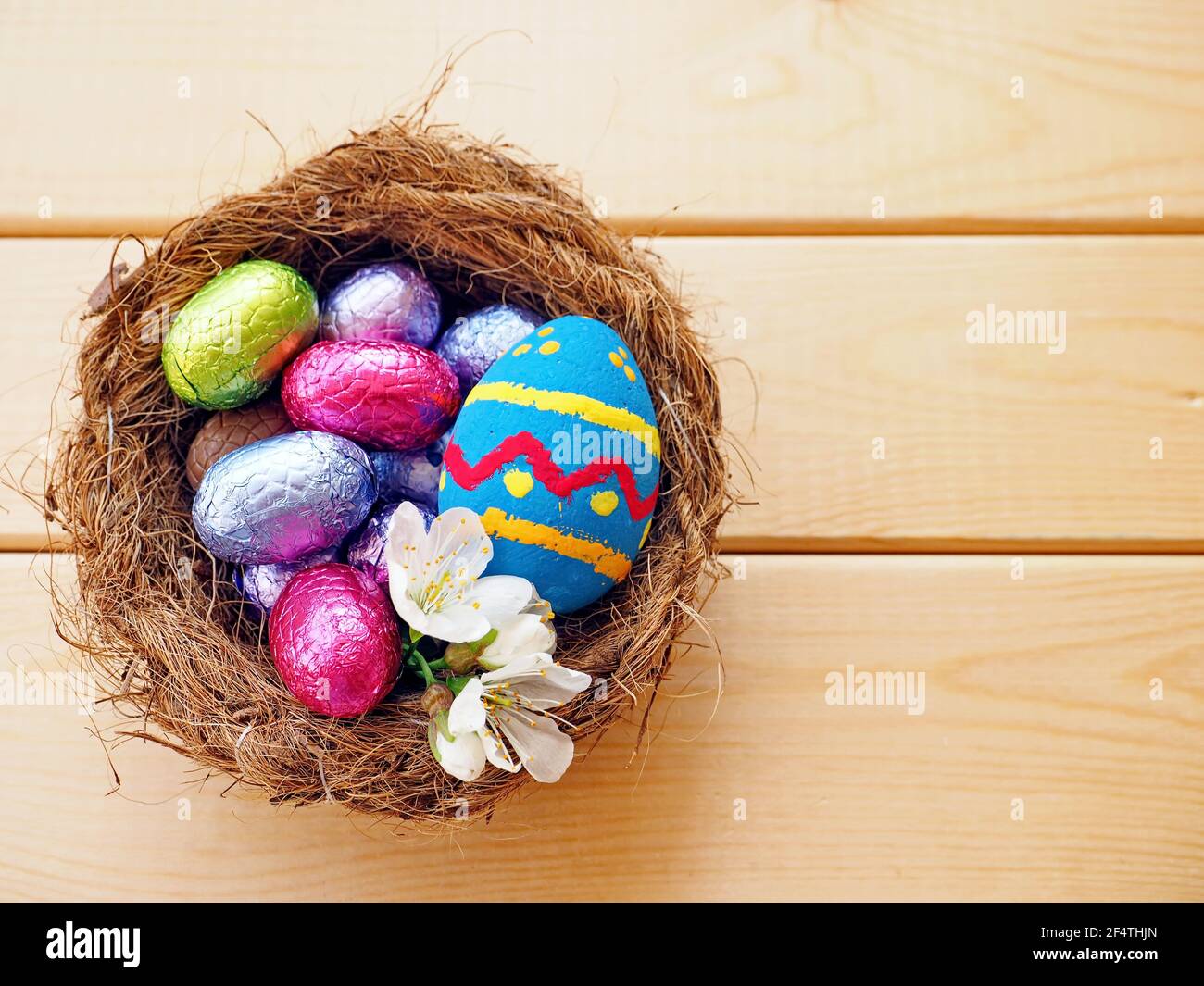 Easter eggs in a wicker basket close up over wooden background Stock Photo
