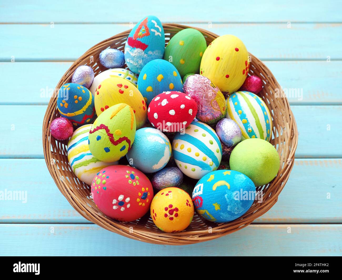 Easter eggs in a wicker basket close up over green blue wood background Stock Photo