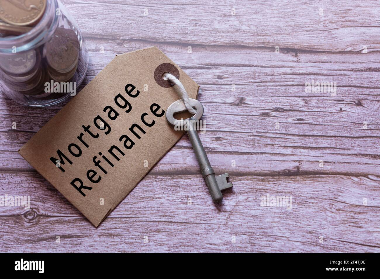 Text on brown tag with key and blurred jar full of coins on wooden table Stock Photo