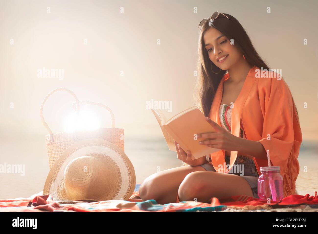A YOUNG WOMAN READING A BOOK WHILE SITTING ON A BEACH Stock Photo - Alamy