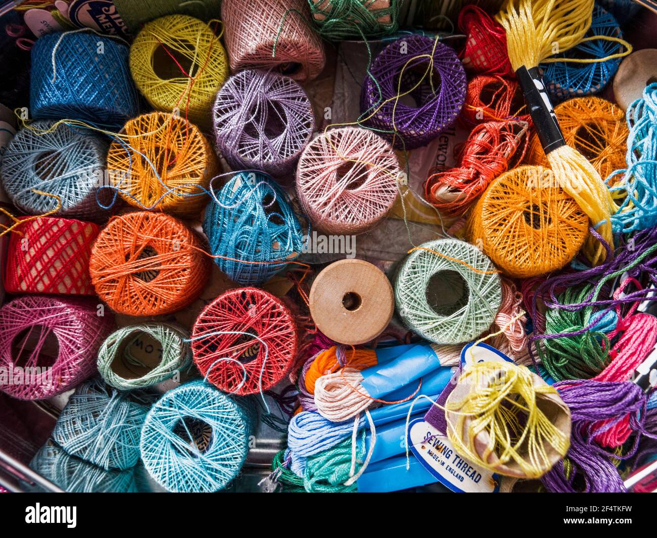 An array of colours in a sewing box with threads of various lengths and ...