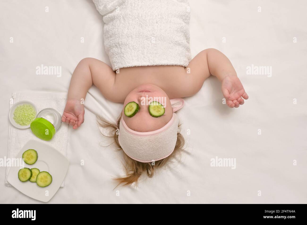 Little Baby Girl Enjoy Spa Applying Cucumber On Face Stock Photo
