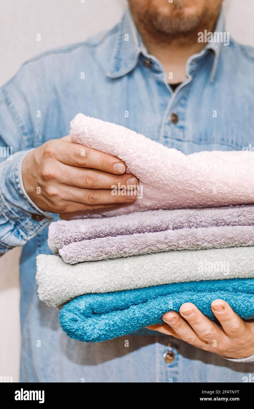 Man holds stack of fresh terry towels. Organization and cleaning