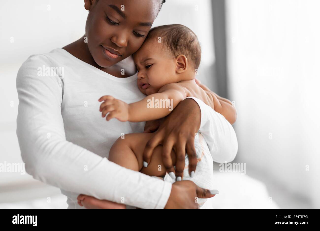 Portrait of black mother holding crying baby on hands Stock Photo