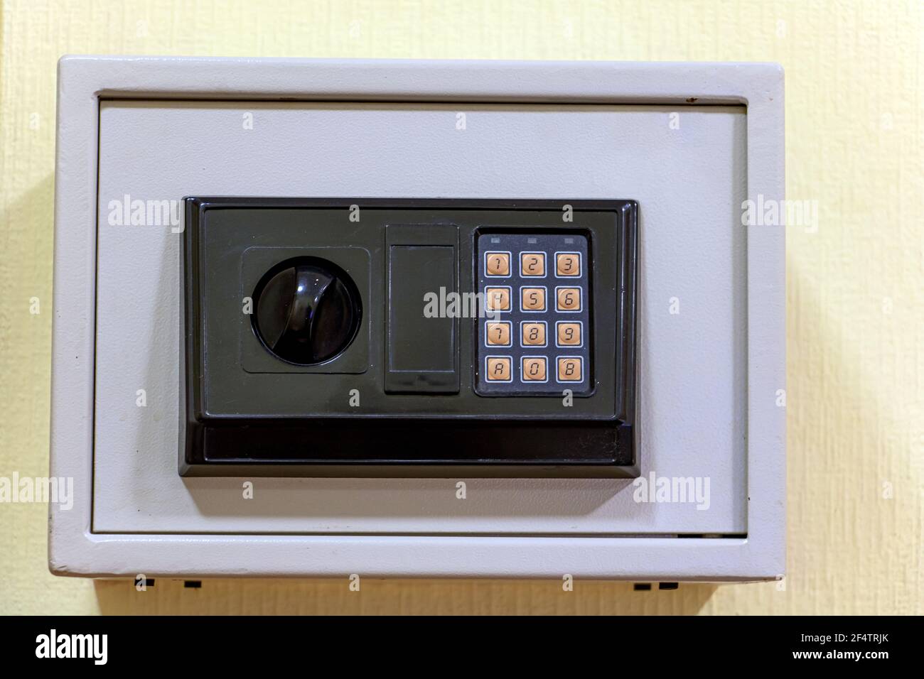 A small safe with a dial is mounted on the wall. Stock Photo