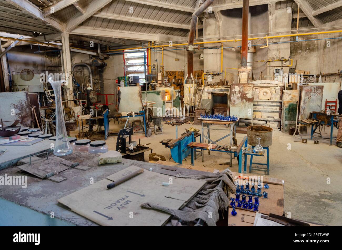 Interior of the glass workshop forgery with it's tools, large ovens, glass figures butane gas bottles, shelves, air dryers, boxes in Poble Espanyol. Stock Photo