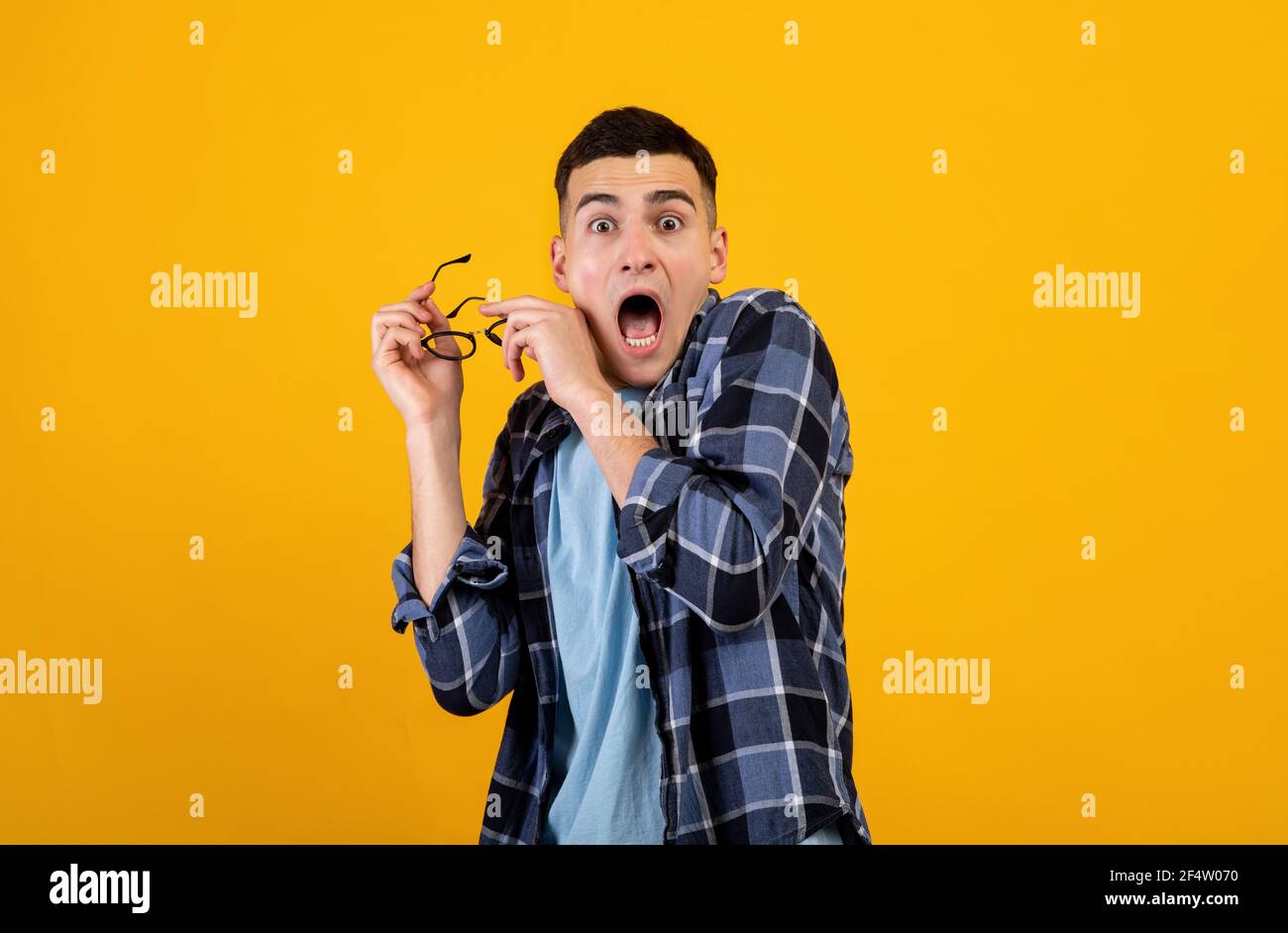 Horrified young guy yelling in panic, taking off his glasses over orange studio background Stock Photo