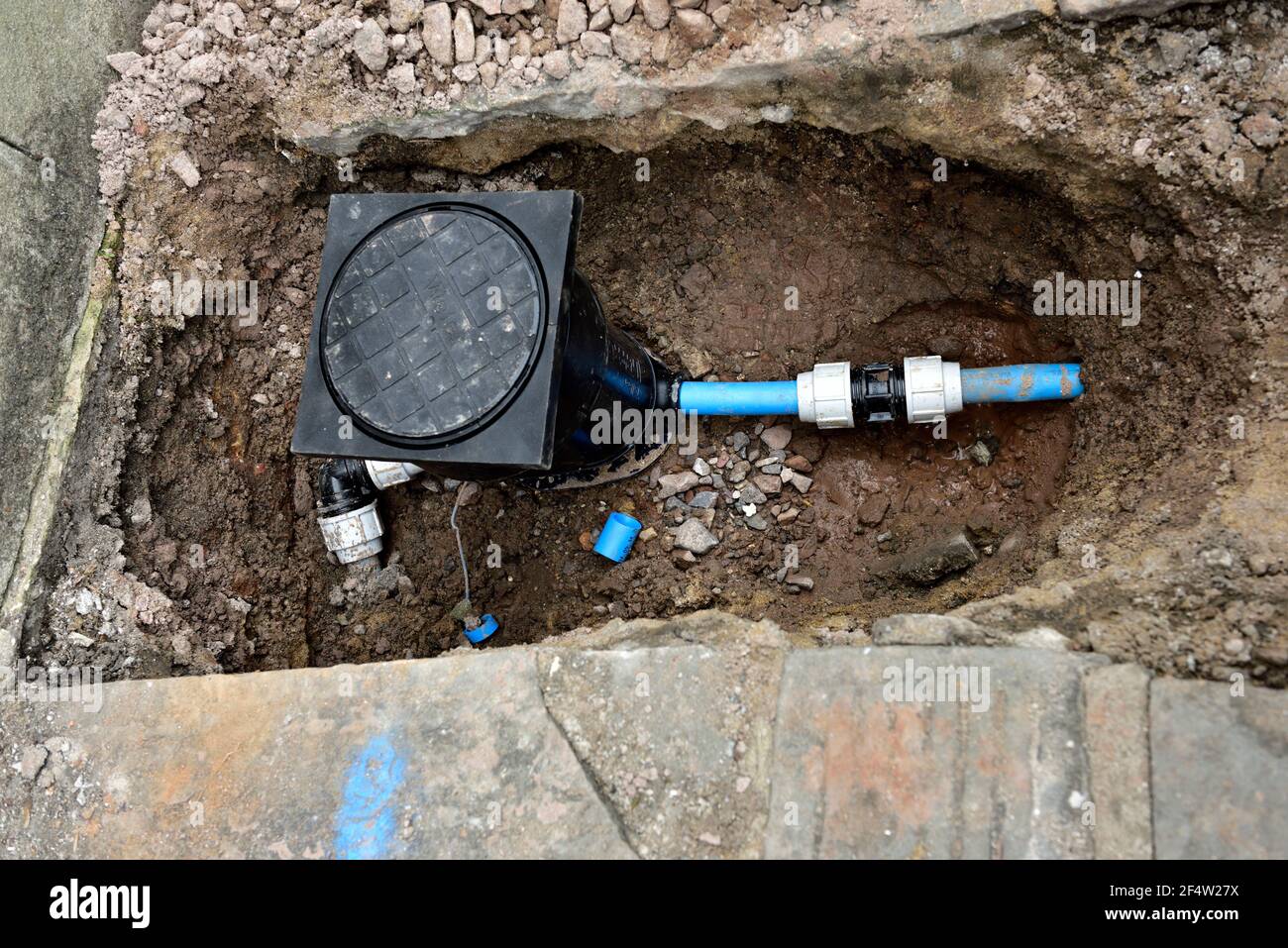 Water meter and stopcock instillation in pavement with new plastic pipe, UK Stock Photo