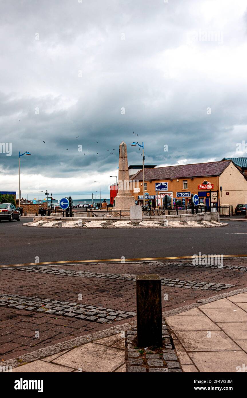The grade 11 listed building, Seahouses war memorial, is situated in the centre of a large traffic island bordered on one side by shops Stock Photo
