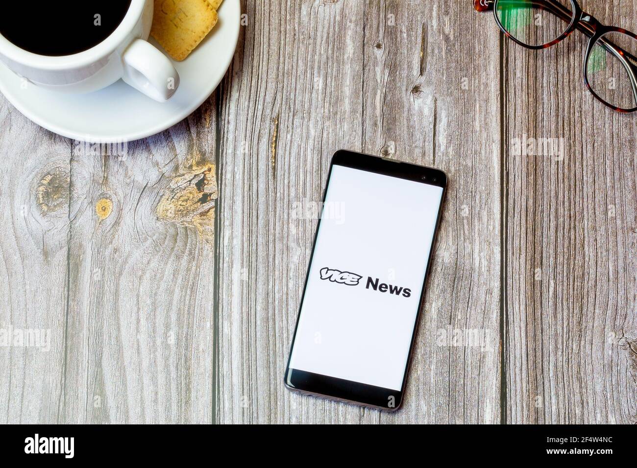 A mobile phone or cell phone laid on a wooden table with the Vice news app open on screen Stock Photo