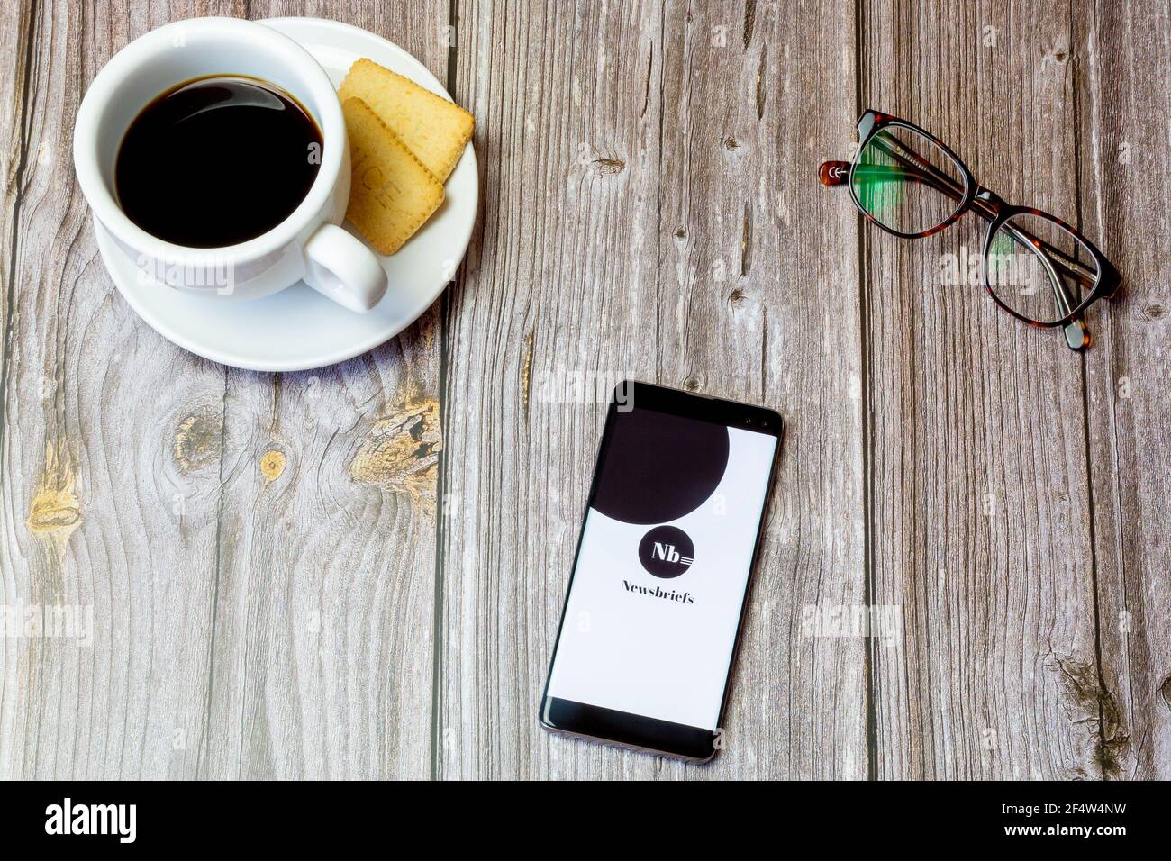 A mobile phone or cell phone laid on a wooden table with the Newsbriefs ...