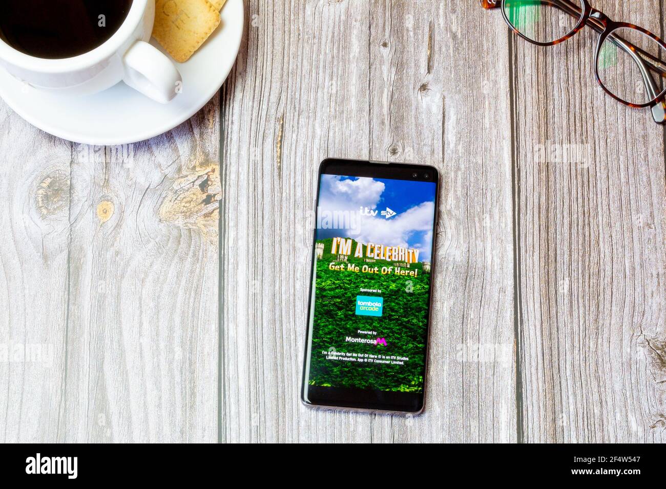 A mobile phone or cell phone laid on a wooden table with the I'm a  celebrity get me out of here app open on screen Stock Photo - Alamy