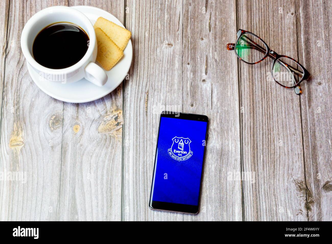 A mobile phone or cell phone laid on a wooden table with the Everton football club app open on screen Stock Photo