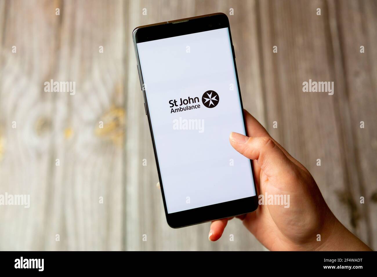 A mobile phone or cell phone being held in a hand with the St John ambulance first aid app open