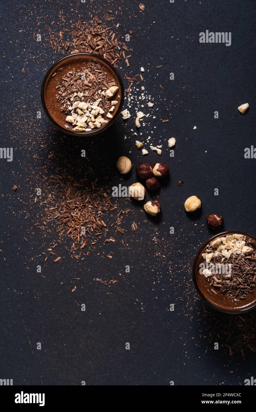 Homemade dark chocolate mousse with hazelnuts in glasses on dark grey table, close up, top view Stock Photo