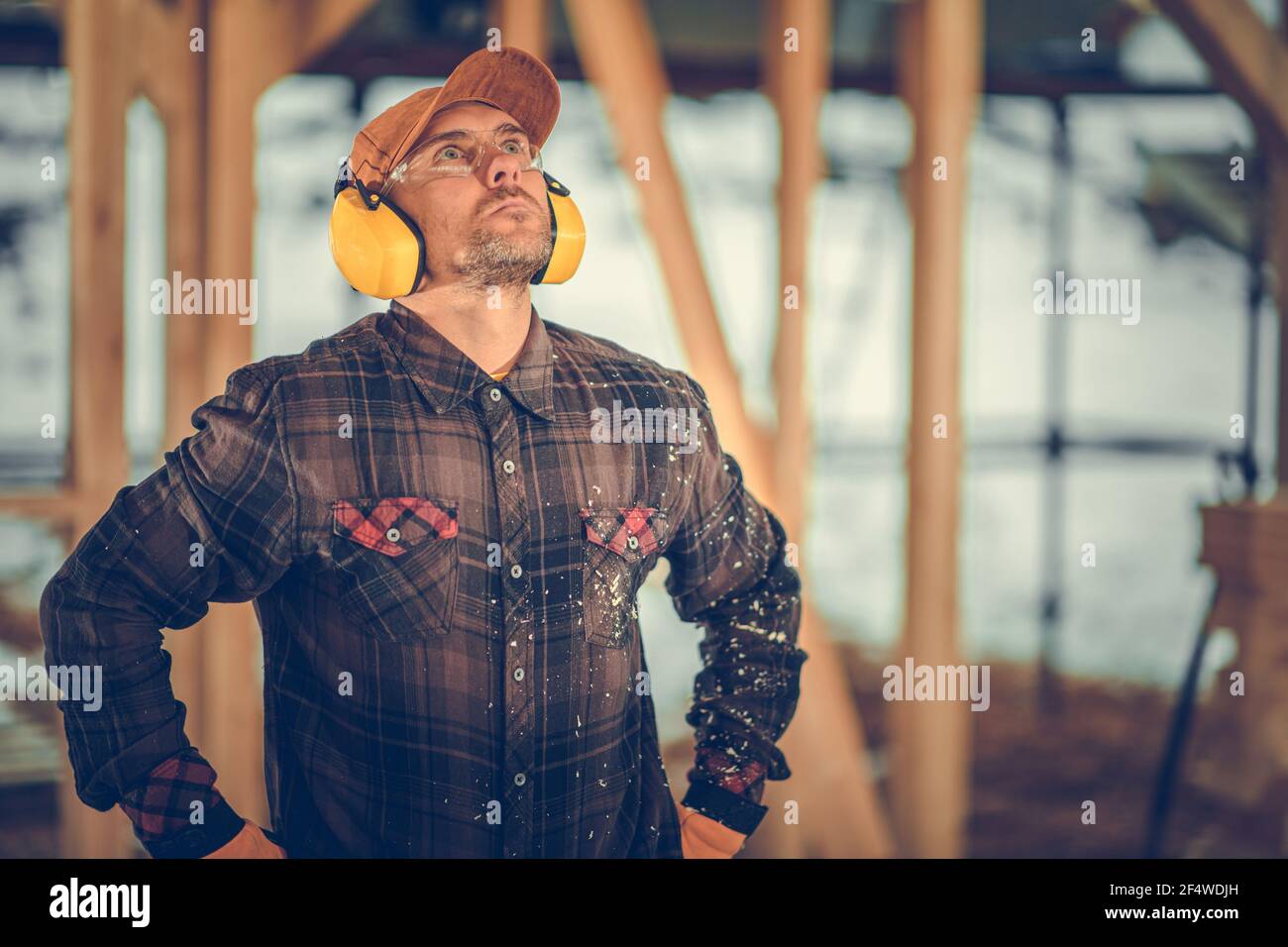 Construction Contractor in His 40s Wearing Noise Reduction Headphones and Eyes Protection Glasses Looking Up Inside Construction Zone. Stock Photo