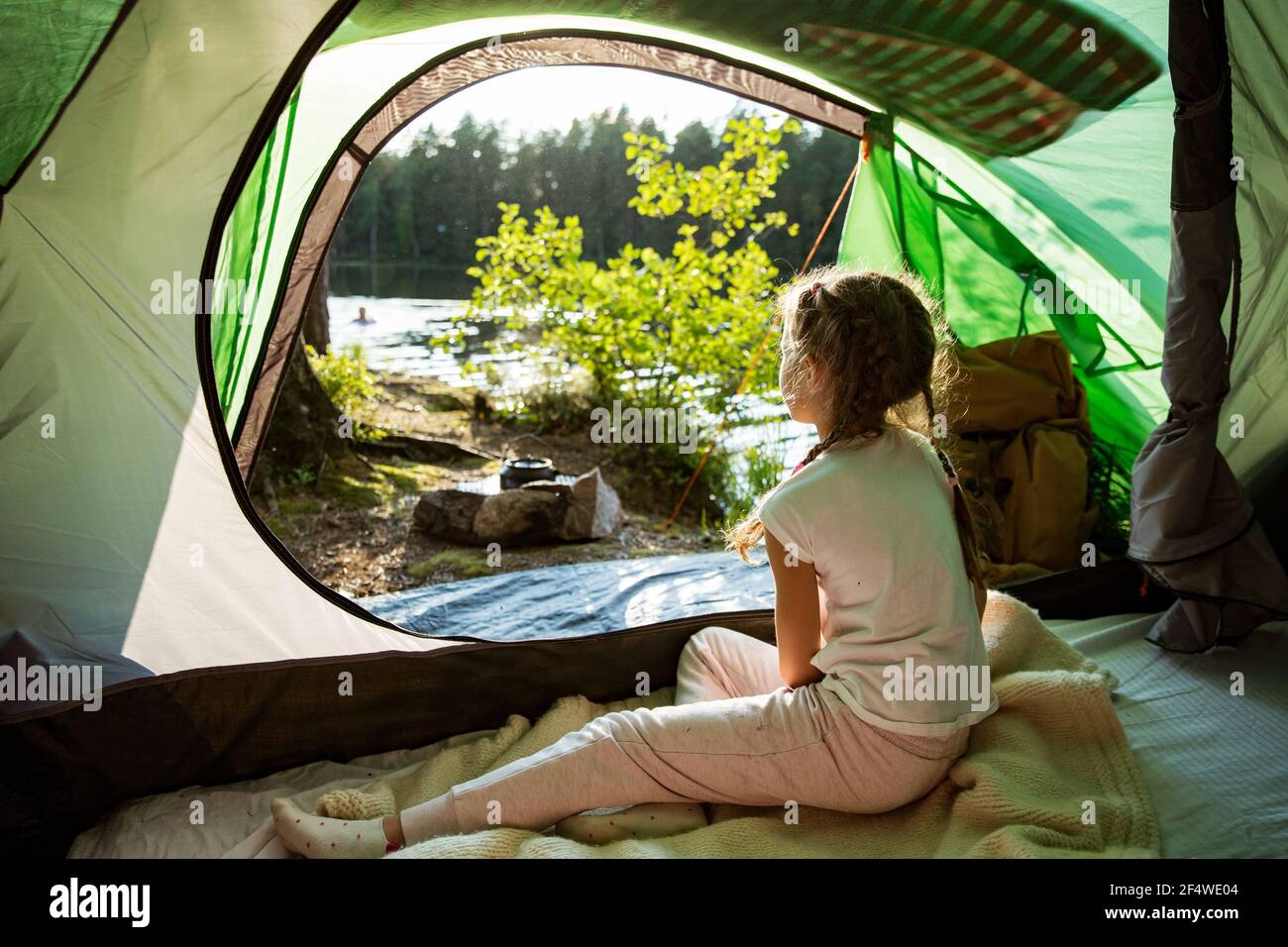 Little girl sitting in tent next to campfire in forest on shore of a lake,  enjoying summer sunny morning. Happy isolation concept. Exploring Finland  Stock Photo - Alamy