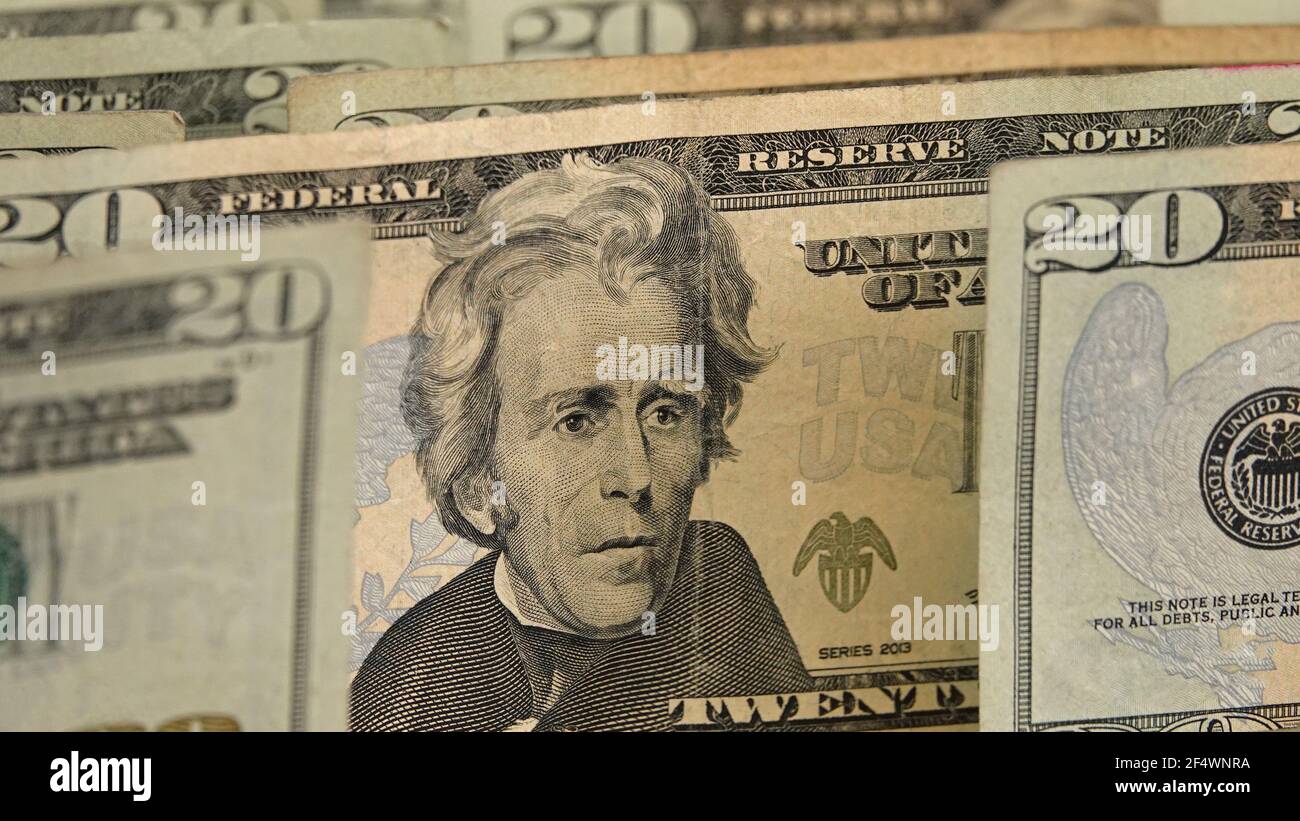 The face of Andrew Jackson on a U.S.A. $20 dollar bill is shown up close, standing among other currency notes of the same denomination. Stock Photo