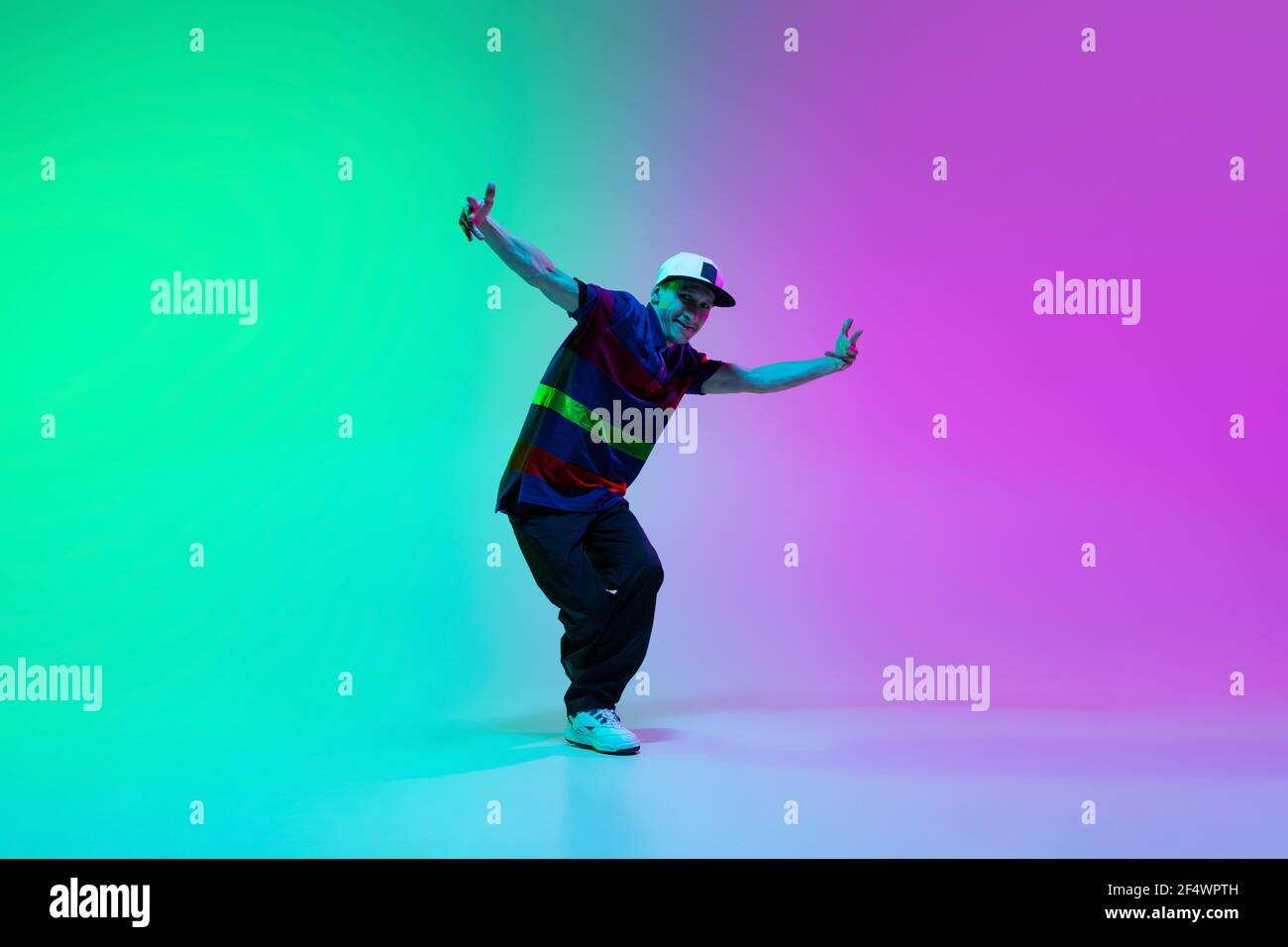 Beautiful sportive boy dancing hiphop in stylish clothes on colorful