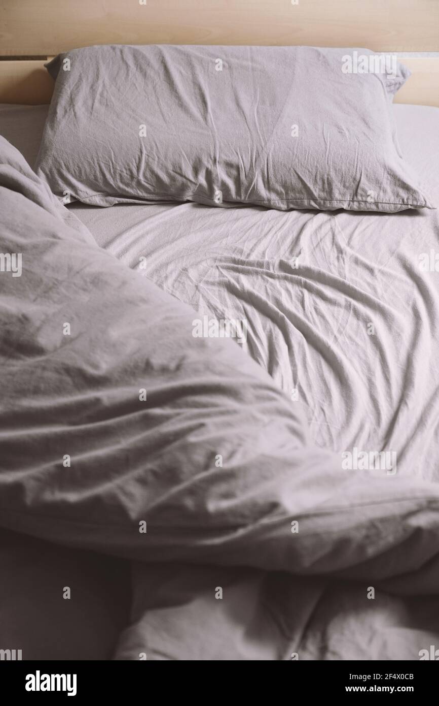 empty unmade bed with crumpled bedding or bedclothes Stock Photo