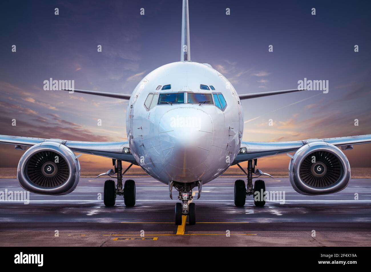 commercial airplane at an airfield against a sunset Stock Photo