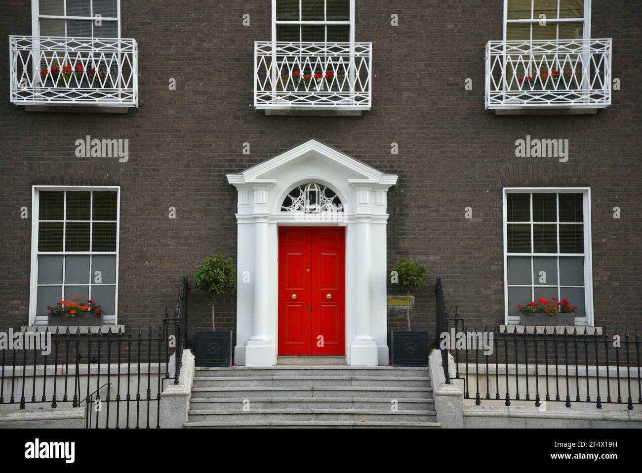 style old brick building facade with a bright red entrance door and symmetrical windows