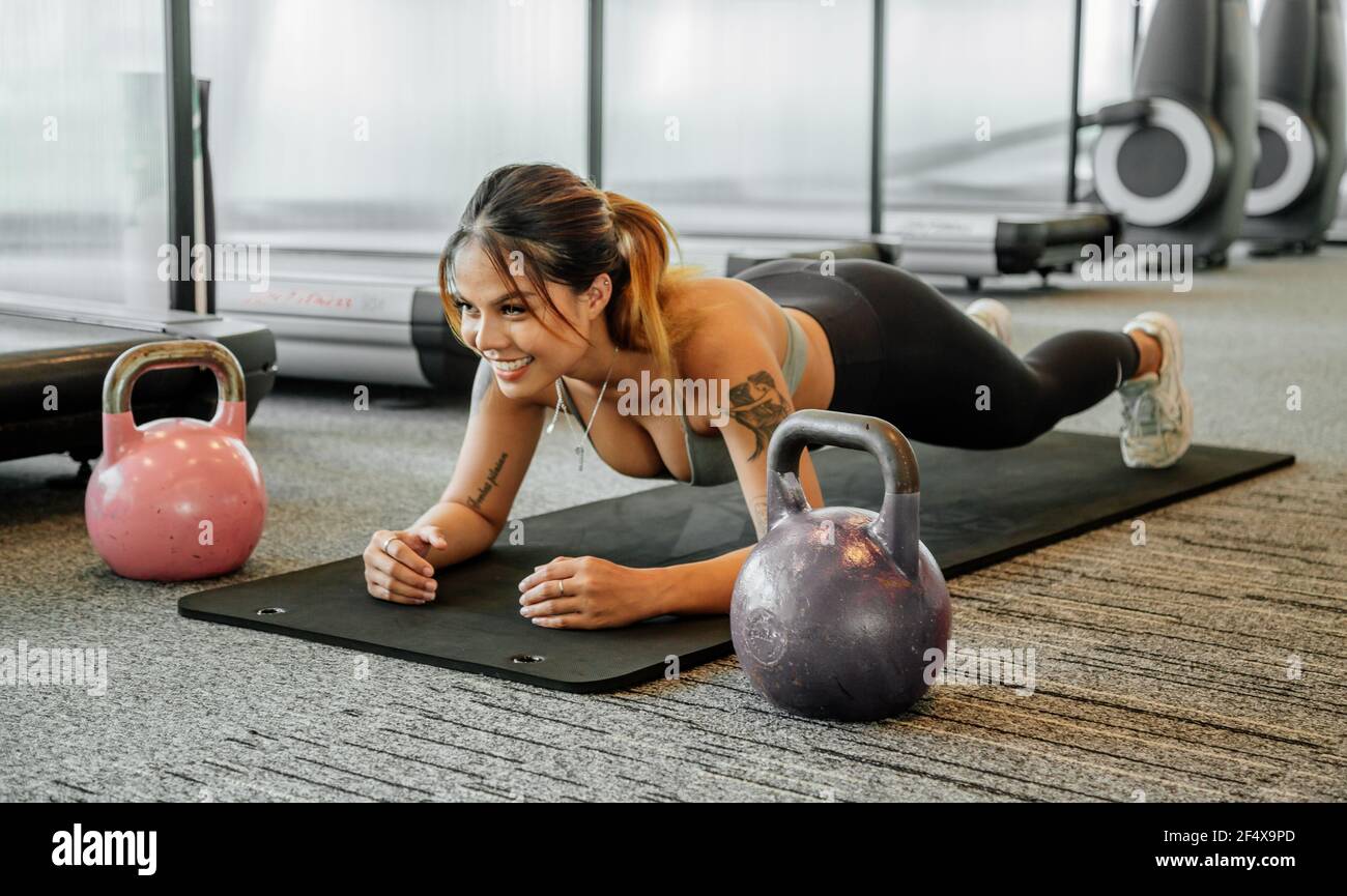 Asian sports woman in the gym, athletes training, workout lifting weight, plank and push up. tattoo thai girl Stock Photo
