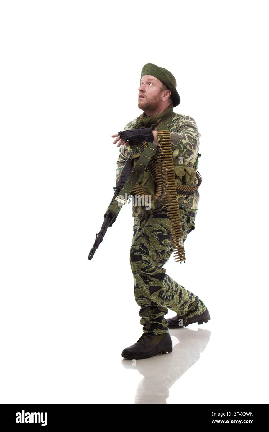 Man actor in the form of an American fur seal posing with a machine gun in his hands on a white background. Special Forces in Vietnam, 1970's. Stock Photo